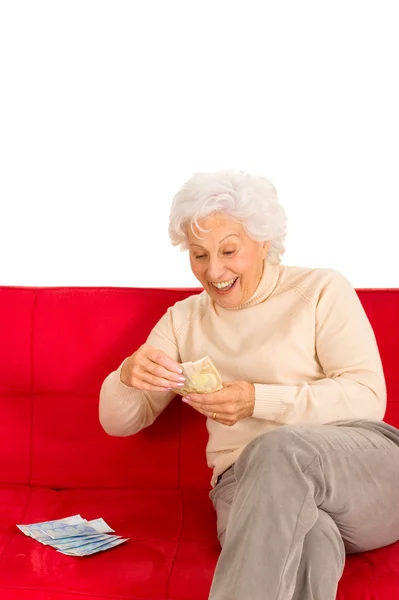 Пожилая женщина на диване с деньгами в руке — стоковое фото