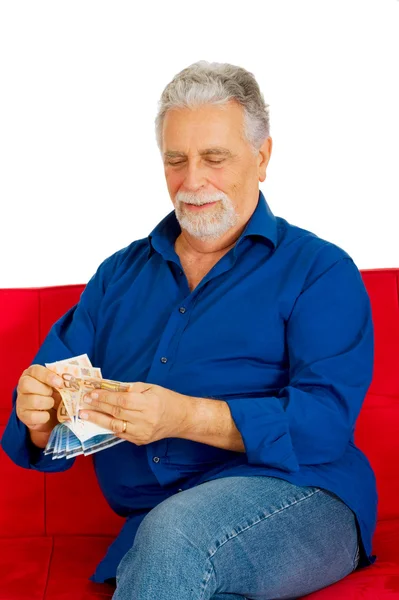 Пожилой человек на диване с деньгами в руке — стоковое фото