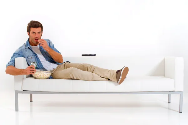 Hombre soltero en el sofá viendo la televisión Imagen De Stock