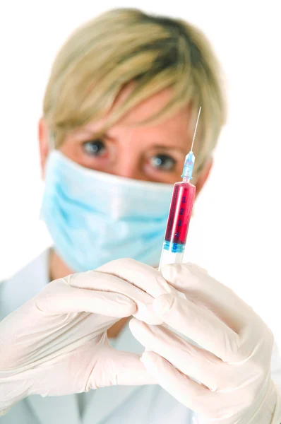 Женщина-врач в маске, держащая шприц — стоковое фото