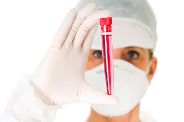 Médica com máscara segurando um tubo de ensaio — Fotografia de Stock