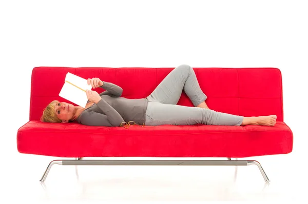 Frau liegt auf der Couch und liest ein Buch — Stockfoto