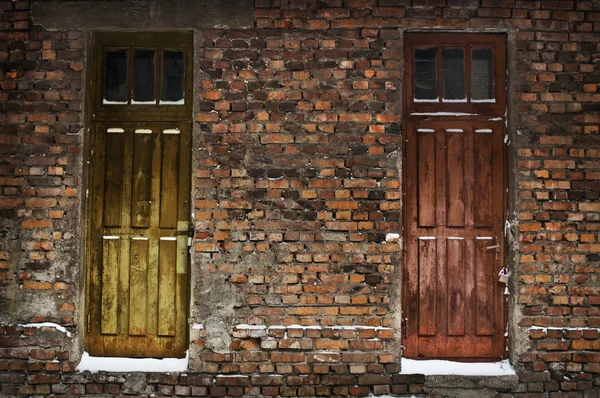Duas velhas portas de madeira na parede de tijolo — Fotografia de Stock