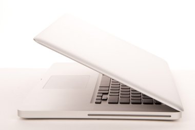 Opened laptop computer from side with modern and stylish keyboard, touch pad and CD/DVD on white background clipart