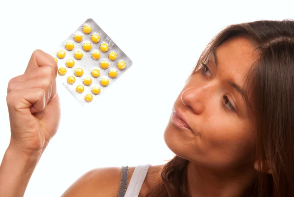 Jovem mulher olhando para comprimidos de comprimidos amarelos — Fotografia de Stock