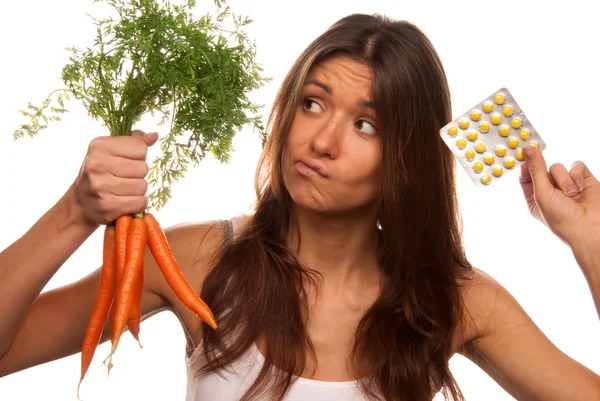Девушка с таблетками и морковью — стоковое фото