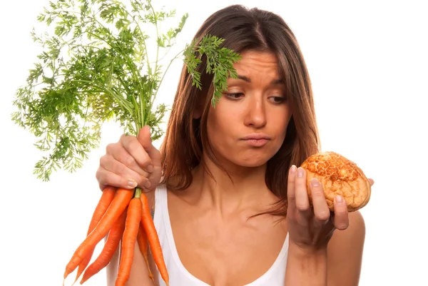 Woman holding bunch of fresh carrots and roll — Stock Photo, Image