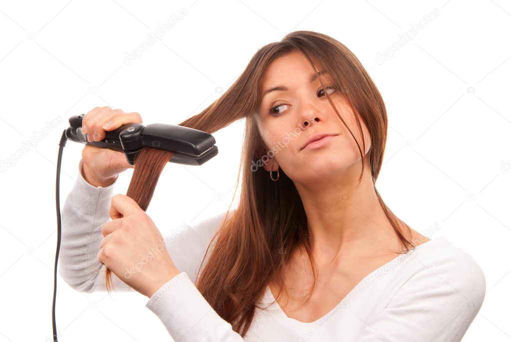 Young brunette woman using hair straighteners black flat iron to make new stylish hairstyle isolated on a white background