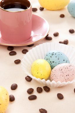 Pazar sabahı pembe, mavi ve sarı yumurta, fincan espresso kahve ve pastel renk arka plan üzerinde mutlu bir Hıristiyan aile için fasulye Paskalya yortusu yumurta