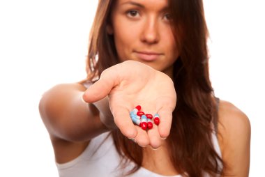 Brunette female doctor offering pills capsules red and blue to the patient in hand and looking at camera isolated on a white background. Focus on tablets clipart