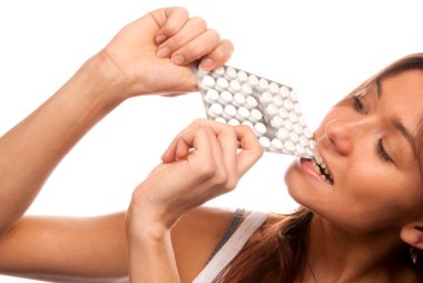 Brunette Woman bite the pack of medicine aspirin tablet pills, she is holding tablets in hands and looking isolated on white background clipart