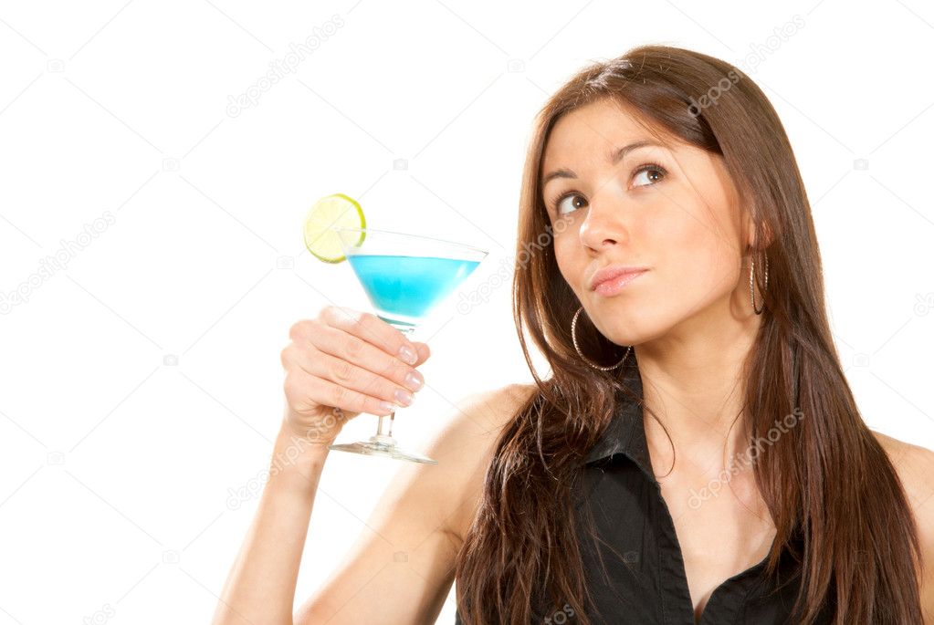 Pretty brunette woman holding popular blue tropical martini cocktail with lime in right hand in black shirt thinking and looking up isolated on a white backgrou