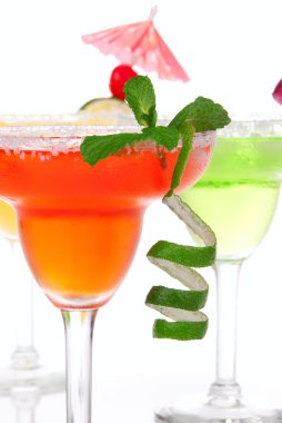 Strawberry, lime, apple Margaritas cocktails composition decorated with twisted lime, mint, cherry, cocktail umbrella in margarita glass isolated on a white bac clipart