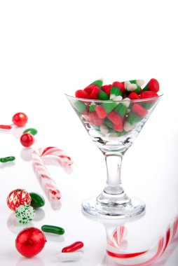 Christmas candies, canes and candy-corn in martini glass isolated on a white background clipart