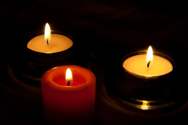 Три свечи в темноте — стоковое фото