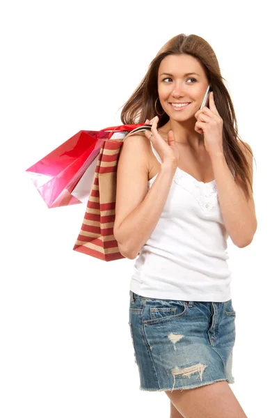 Mujer joven hablando por teléfono con bolsas de compras en la mano —  Fotos de Stock