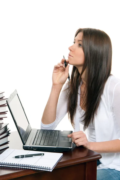 Kobieta siedząca z laptopem z piórem w ręku — Zdjęcie stockowe
