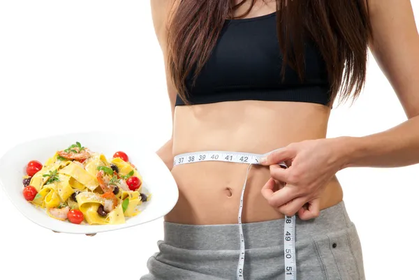 Woman measuring waist and holding diet food — Stock Photo, Image