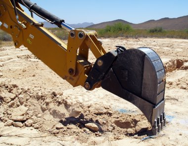 A construction Back Hoe digging the footing for a foundation that has been precisely marked. clipart