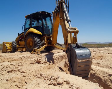 A construction Back Hoe digging the footings for a foundation. clipart