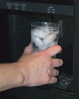 Someone filling their glass up with water at the refrigerator door. clipart