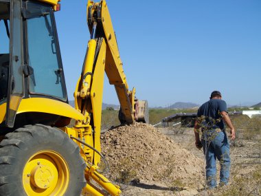 A construction worker inspecting a hole he had just dug in the Arizona desert. clipart