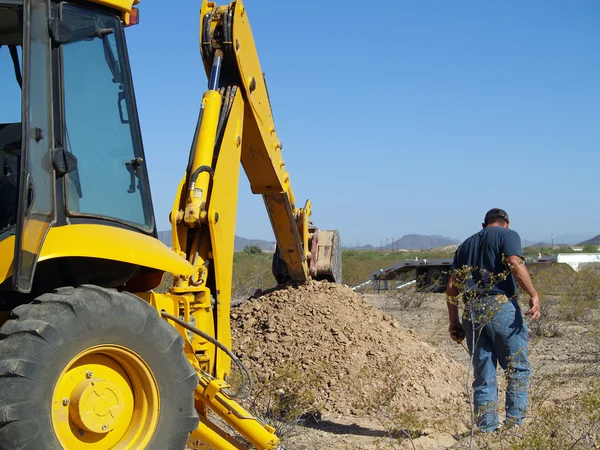 stock image A construction worker inspecting a hole he had just dug in the Arizona desert.