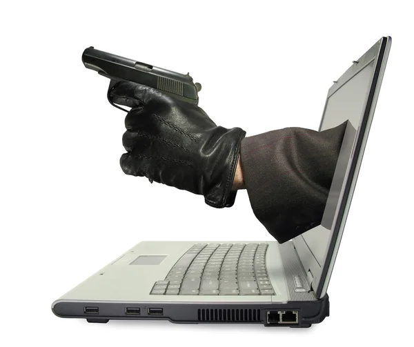 Ноутбук с рукой и пистолетом торчит из монитора. Концепция интернет-пиратства — стоковое фото