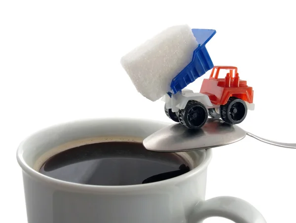 Koffiekopje en lepel met speelgoed vrachtwagen klaar om te laden van de suiker forfaitaire Stockafbeelding