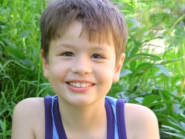 Um menino sorridente em verde — Fotografia de Stock