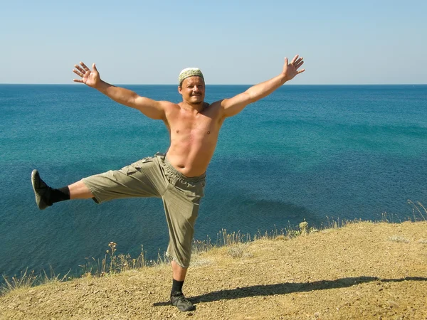 Mannen på stranden står på ett ben, armar utsträckta — Stockfoto