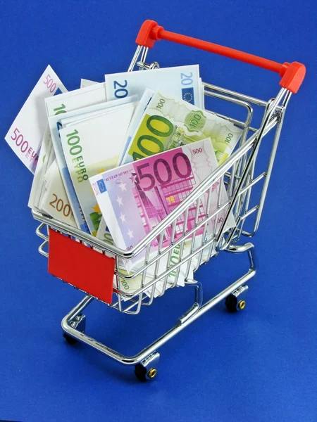 Moneda euro en un carrito de compras sobre un fondo azul — Foto de Stock