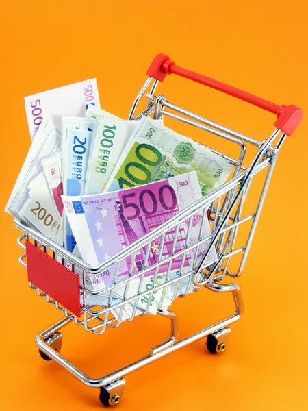 Eurowährung im Einkaufswagen auf orangefarbenem Hintergrund — Stockfoto
