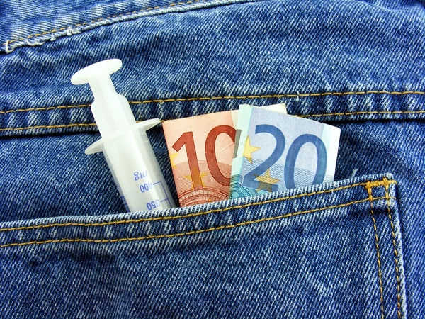 Dinero de drogas - Aguja hipodérmica y dinero en efectivo en el bolsillo trasero — Foto de Stock