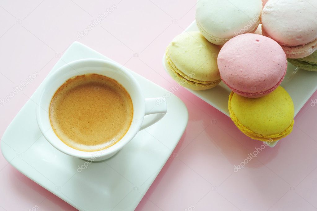 Macaroons and one white cup of coffee on a pink background