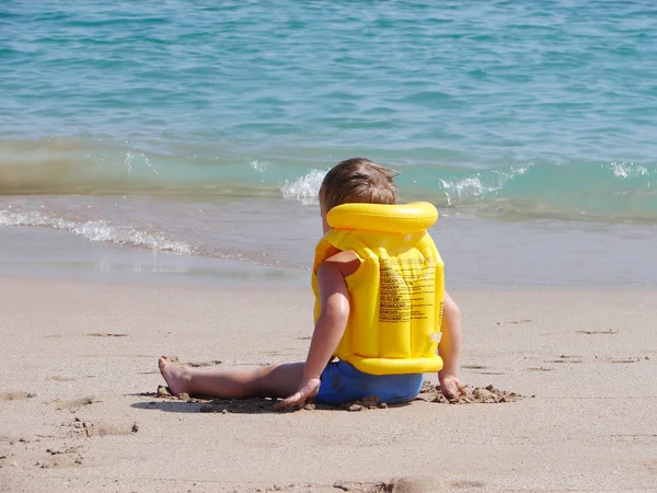 Liitle pojke på stranden i flytväst — Stockfoto