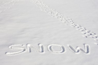 SNOW Written In A Snowy Field Beside Footprints clipart