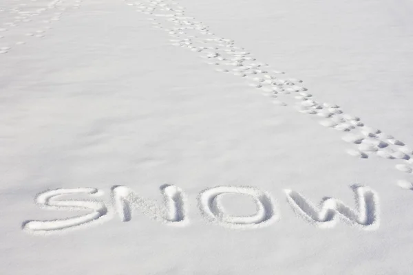 stock image SNOW Written In A Snowy Field Beside Footprints