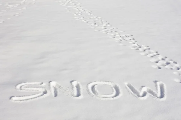 SNOW Written In A Snowy Field Beside Footprints 스톡 사진