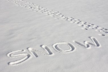 SNOW Written In A Snowy Field Beside Footprints clipart