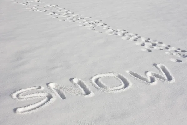 stock image SNOW Written In A Snowy Field Beside Footprints