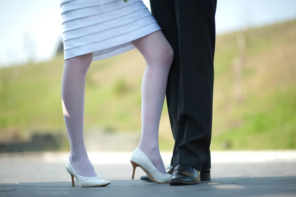 stock image Feet of the groom and the bride adjoin knees on a dim back background