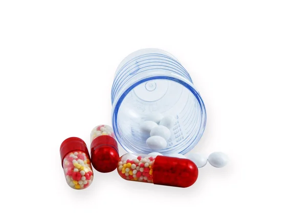 Tablets and pilbli in a plastic beaker — Stock Photo, Image