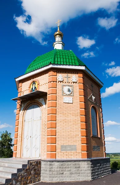 stock image A small chapel on a background of blue sky with clouds