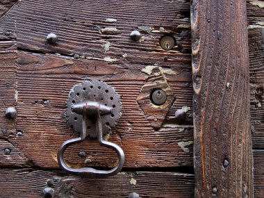 Rusty iron door knocker - decorative and ornate detail home object. Vintage architecture of Italy. Residential building with a wooden entrance door. clipart