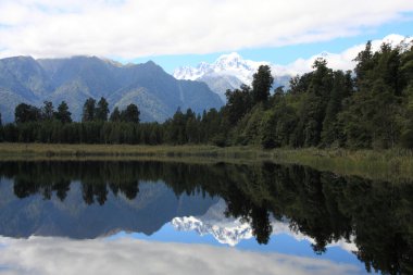 New Zealand. Lake Matheson - famous view with reflection of snowy Mount Tasman and Mount Cook. Westland district. clipart
