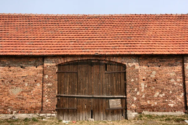 Старый кирпичный амбар с деревянными воротами — стоковое фото