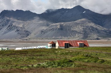 Old red roofed farm in Lonsoraefi mountains in Iceland. HDR photo. clipart