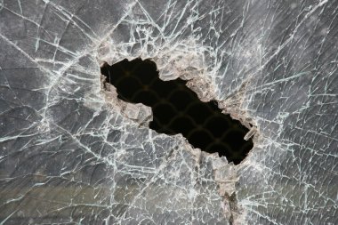 Broken window of armoured glass. Bulletproof glass hole. clipart