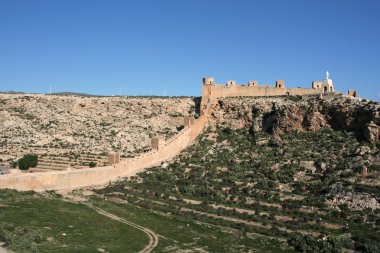 Alcazaba - fortified Moorish castle on a hill in Almeria, Andalusia, Spain. Christ statue. clipart